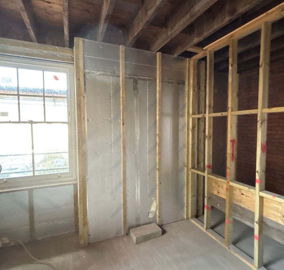 Foil-faced insulation fitted between battens on an external wall